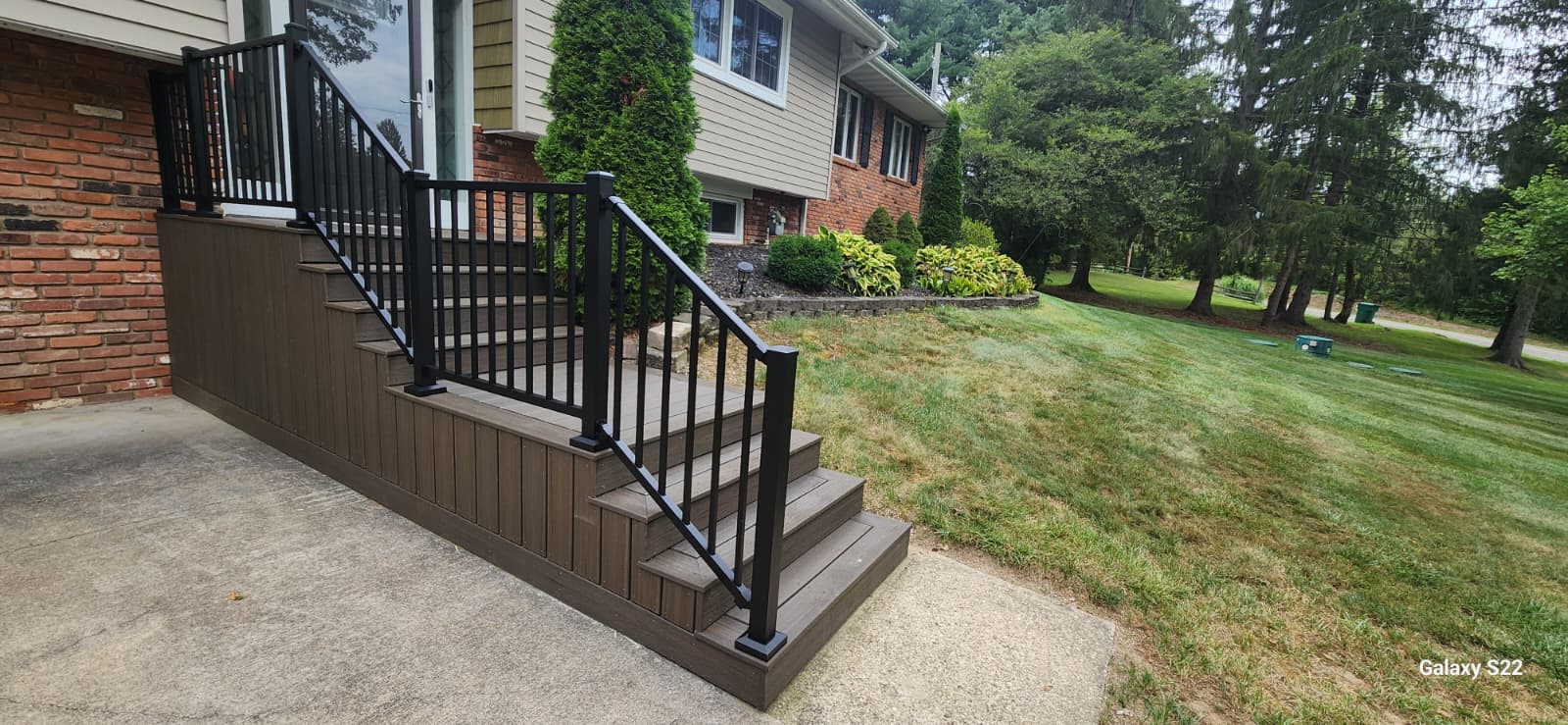 Finished exterior stairs with black railings on a landscaped home